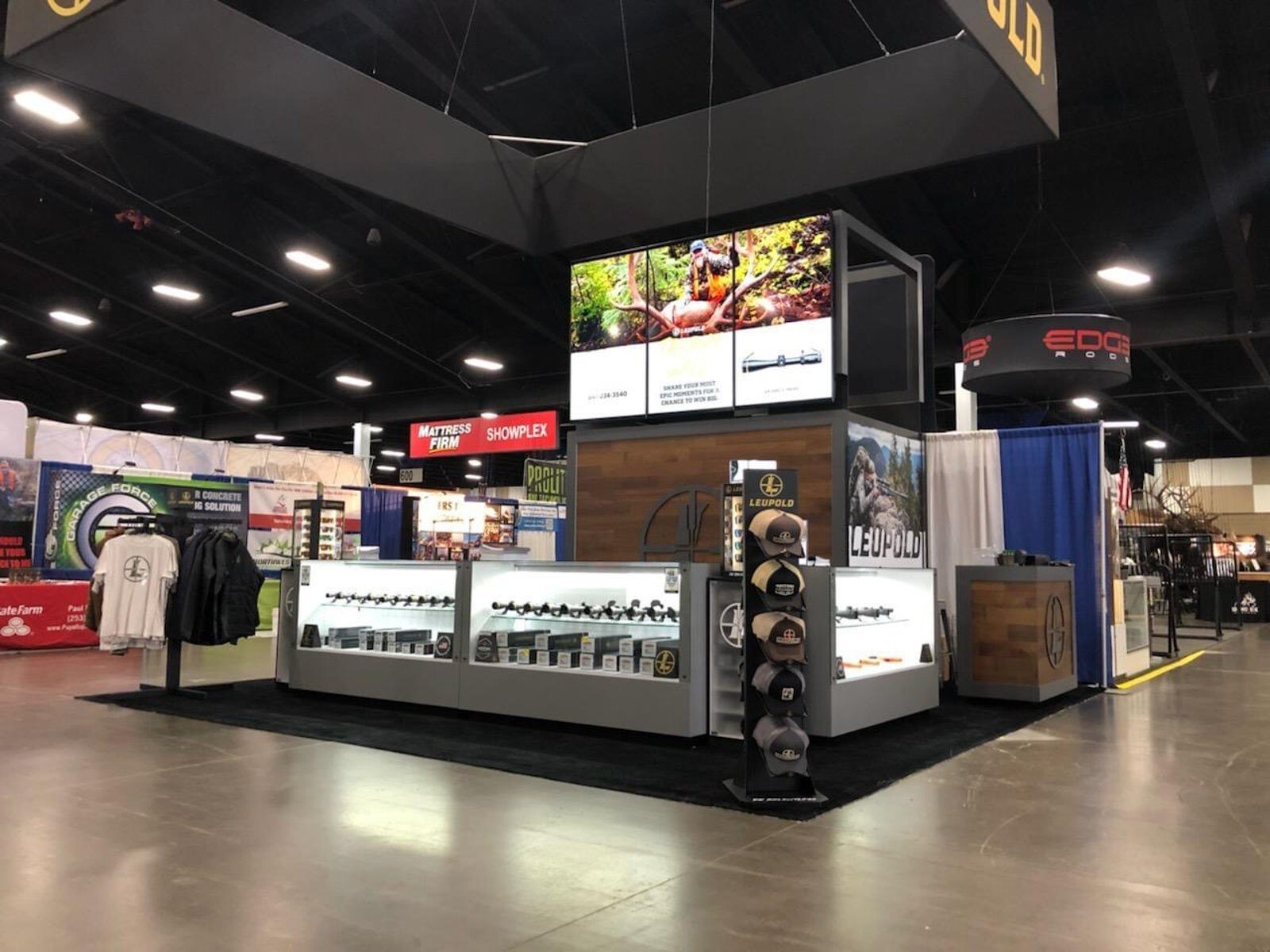 Trade-show booth with a suspended illuminated ring sign over lit product display cases