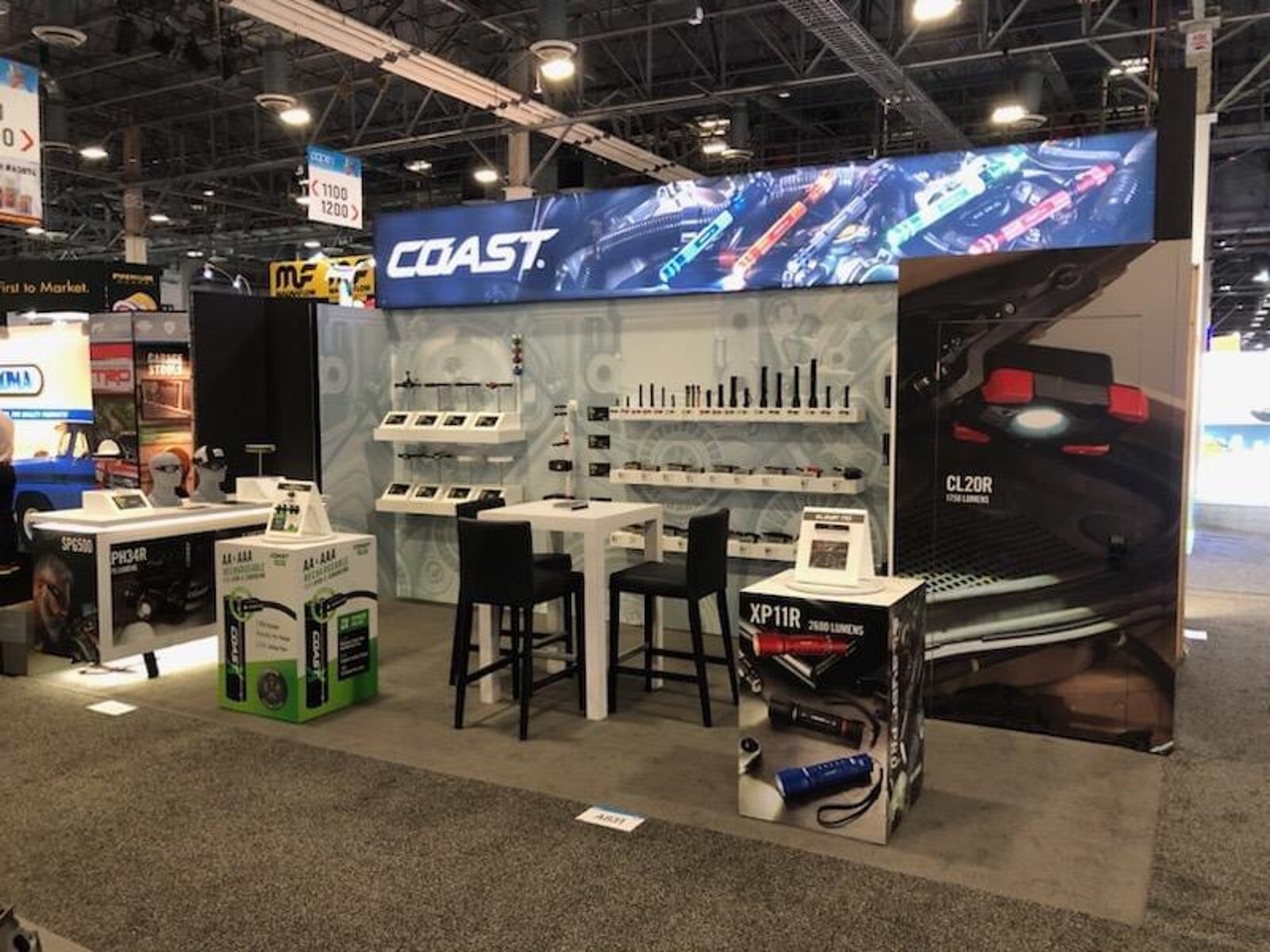 Inline booth with a backlit header banner and a wall of lit product displays