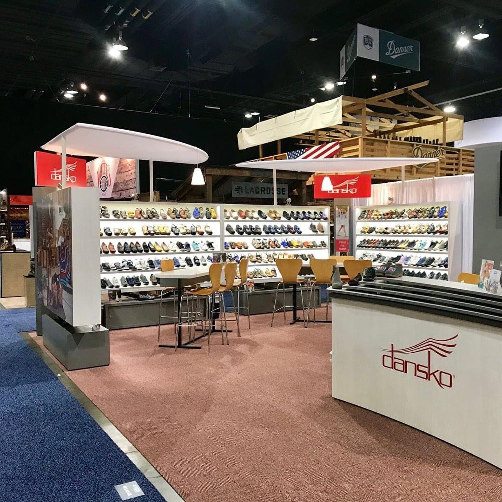 Footwear-display booth with lit wall shelving and suspended canopy fascia