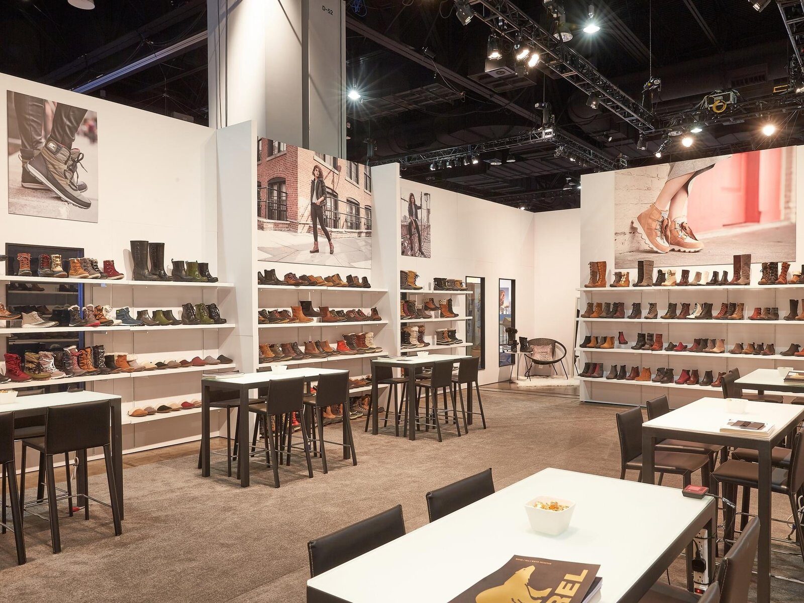 Open showroom booth with large lifestyle photo panels and wall-mounted footwear shelving